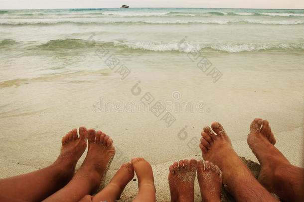 一家人脚踩在沙滩上的沙子上