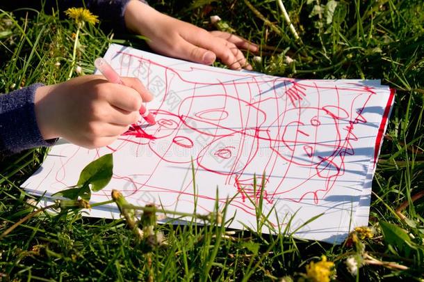 近景儿童手绘彩色装饰品在纸上。 笔记本在草地的新鲜青草中。