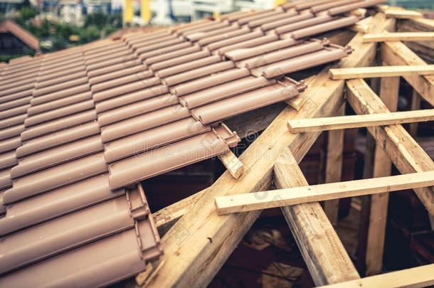 建造新房子，用棕色瓷砖和木材建造屋顶。 承包商建造新房子的屋顶