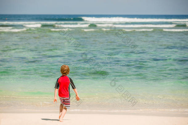 可爱<strong>的</strong>7岁男孩穿着红色<strong>的</strong>鲁西<strong>西游</strong>泳衣在热带海滩与白沙和绿色<strong>的</strong>海洋
