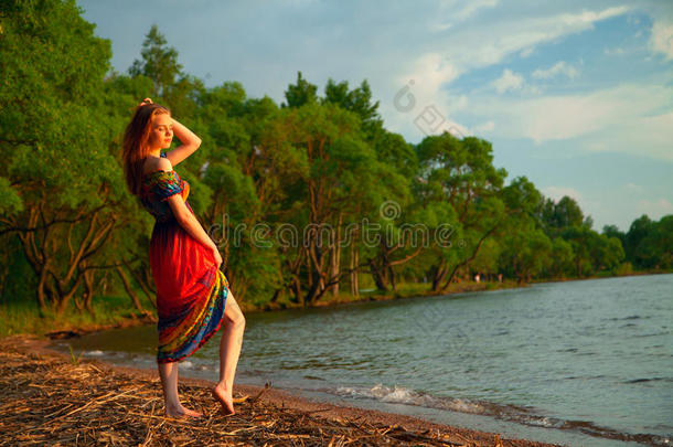 穿着连衣裙的女孩在海边沿着萨的树上散步