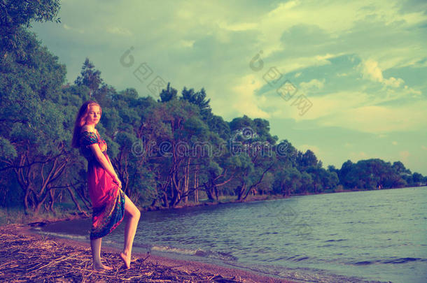 穿着连衣裙的女孩在海边沿着萨的树上散步