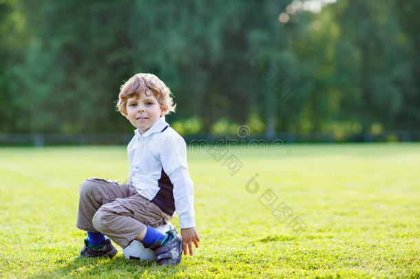 四岁的金发男孩在足球场上踢球休息