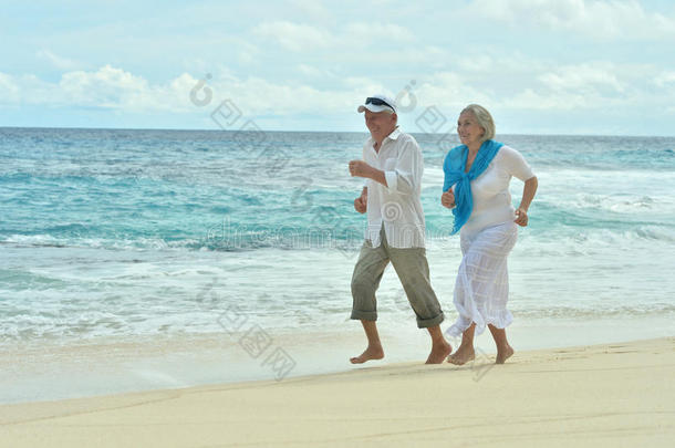 一对老年夫妇在海滩上跑步