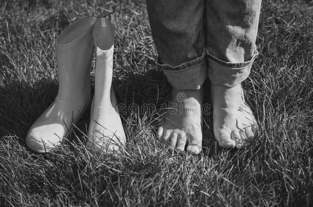 黑白镜头的女孩脱下靴子，站在草地上