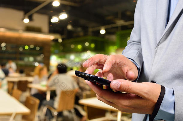 商人在餐厅或美食广场使用移动智能手机
