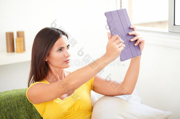 平静的女人坐在室内使用平板电脑