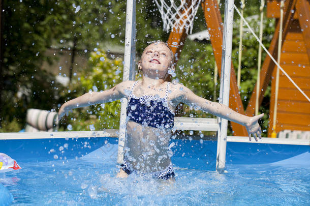 游泳池附近穿蓝色比基尼的女孩。 炎热的夏天