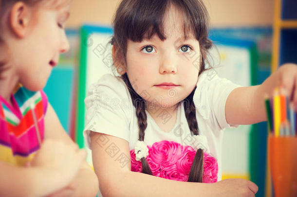 可爱的女孩在幼儿园用<strong>彩色铅笔画</strong>画