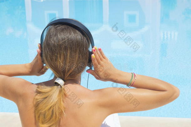女孩在游泳池边听音乐