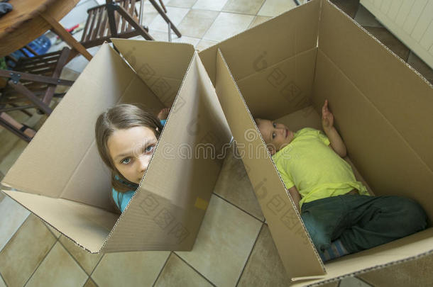 孩子们坐在纸板箱里。 打开箱子搬到一个新家。