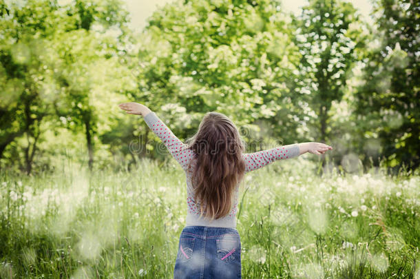 可爱的小女孩在阳光明媚的日子里举起双手站在空中对抗神奇的大自然