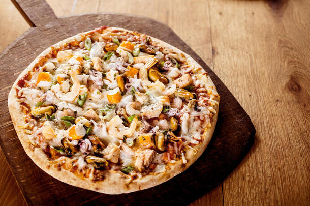 木制砧板上的新鲜烘焙海鲜披萨