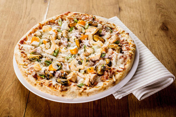 木制桌子上的新鲜烘焙海鲜披萨