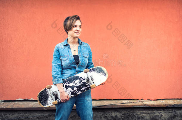 穿着牛仔裤的女孩穿着滑板，孤立在五颜六色的背景上。 健康城市生活方式的概念，潮人