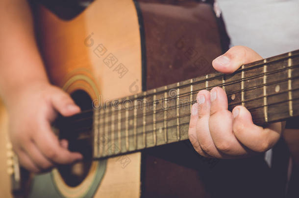 男孩的手指在老式的图像音调中弹吉他。