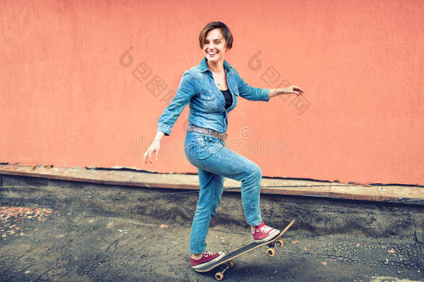 一个黑发可爱的女孩在滑板上的艺术肖像，笑着玩得很开心。 现代生活的健康概念，嬉皮士