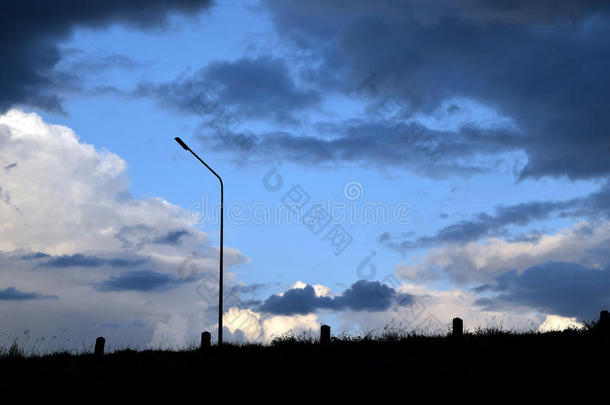 背光灯柱草地和深蓝色暴风雨多云的天空在晚上
