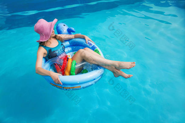 夏天，美丽的女孩漂浮在游泳池里的游泳池里
