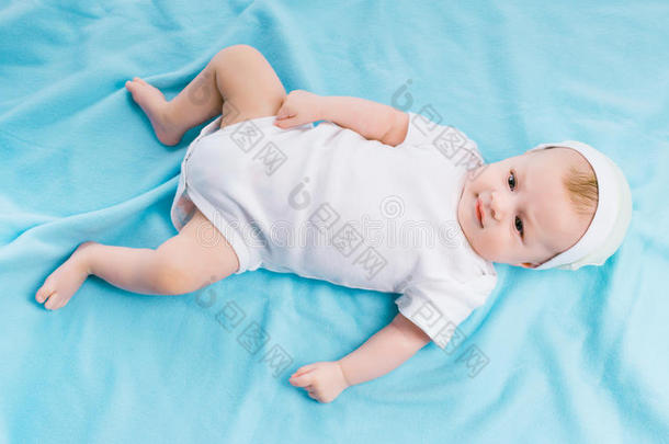 戴帽子的婴儿躺在蓝色的毯子上