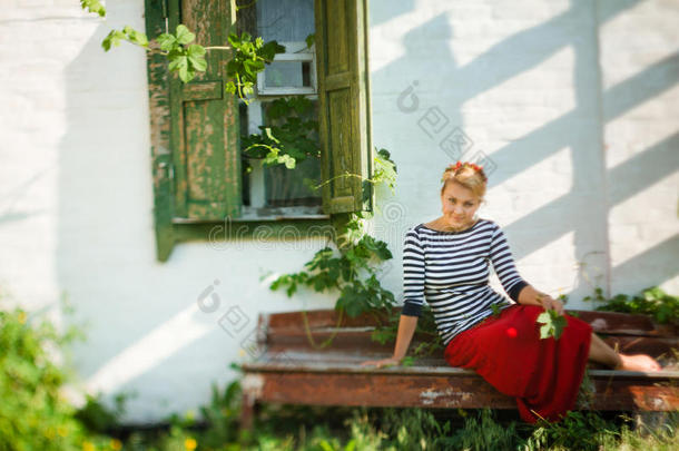 漂亮的女孩坐在乡村房子附近的长凳上