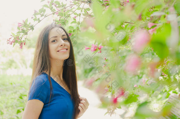 美丽快乐的年轻女人微笑着夏天盛开的树木