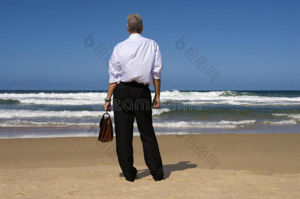 商人站在海滩上放松地看地平线，退休计划的概念