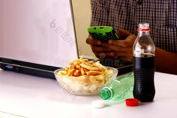 瓶子的软饮料或苏打水，芯片和人使用智能手机和笔记本电脑在后台