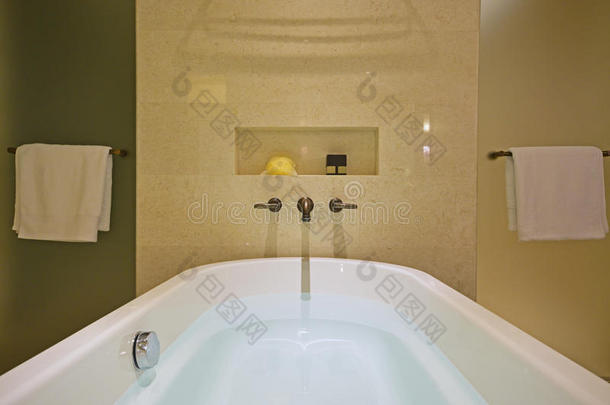 充满白色浴缸与黄铜水龙头安装在大理石墙壁和淋浴屏幕两侧