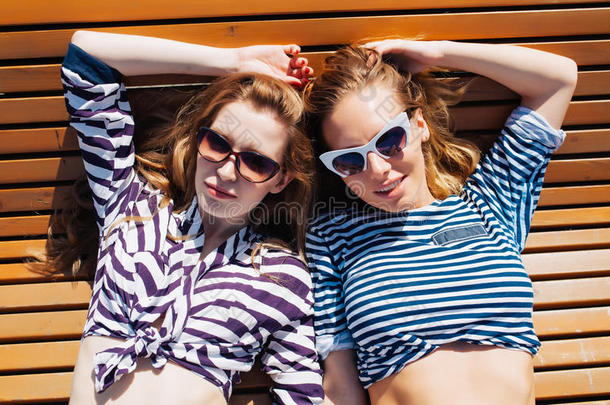 特写夏日生活<strong>写真</strong>两个女孩朋友放松和晒太阳，躺在<strong>沙滩</strong>上，穿着鲜艳的海洋服