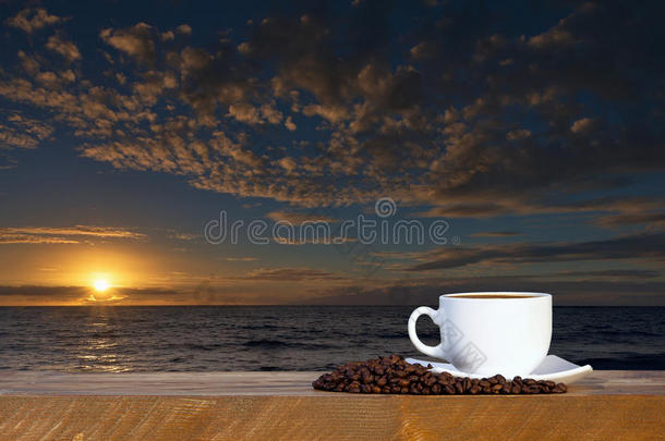 日落或日出海滩木桌上的咖啡杯