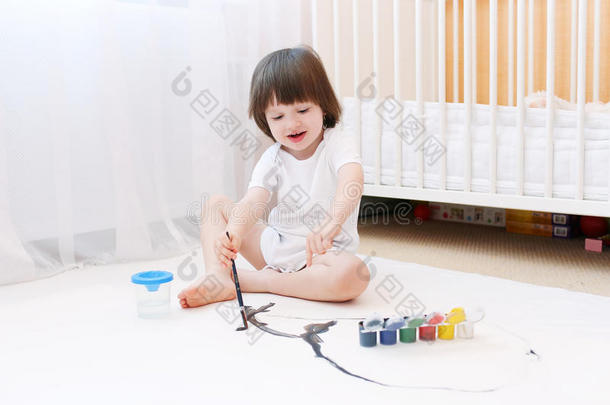 可爱的2岁男孩用刷子和水粉画画