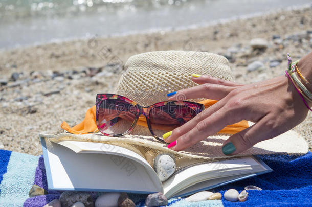 女孩们伸手去拿太阳镜和一本书在海滩上