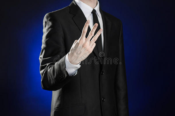 商业和主题的展示：穿着黑色西装的人在工作室孤立的深蓝色背景上展示手势