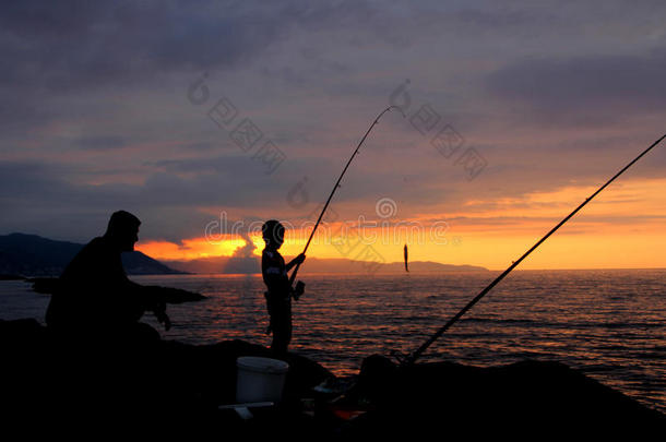 父子在日落时钓鱼的剪影