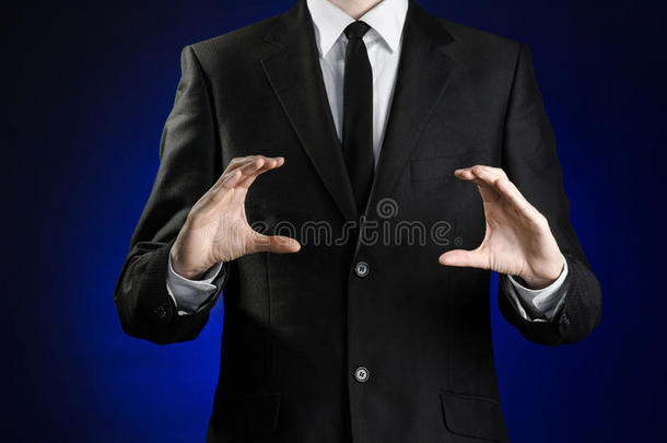 商人和手势主题：一个穿着黑色西装和白色衬衫的男人，用手在深蓝色的背景上展示手势