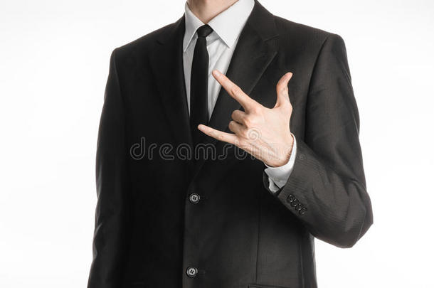 商人和<strong>手势</strong>主题：一个穿着黑色西装，戴着领带的人，在一个孤立的白色背景上展示了<strong>摇滚手势</strong>