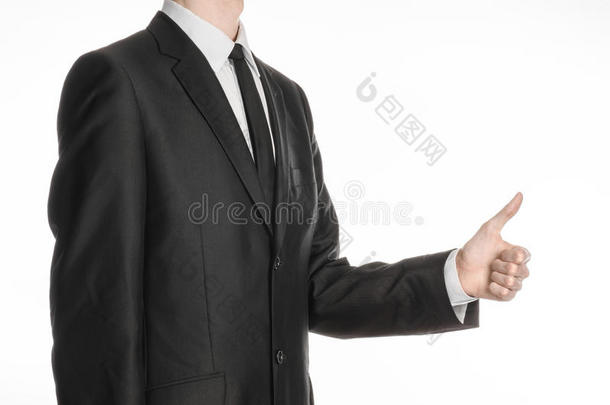 商人和手势主题：一个穿着黑色西装和领带的人在他面前握着他的手，露出孤立在白色上的拇指