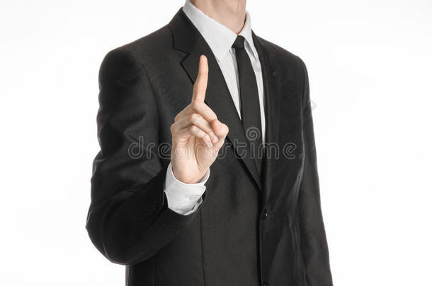 商人和手势主题：一个穿着黑色西装，打着领带的人在白色孤立的背景上显示食指向上