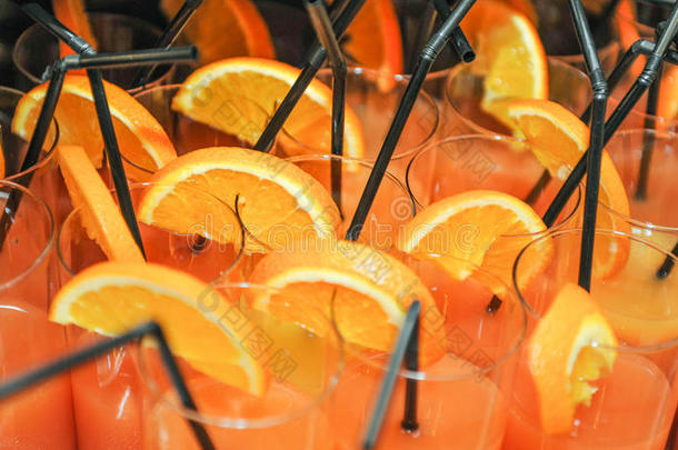 新鲜饮料与橙色片和吸管，关闭。 橙汁在带吸管的玻璃杯里，准备喝