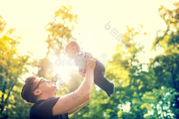 父亲<strong>抱着孩子</strong>，把<strong>孩子</strong>扔在空中。 幸福家庭的概念，逆光的复古效果