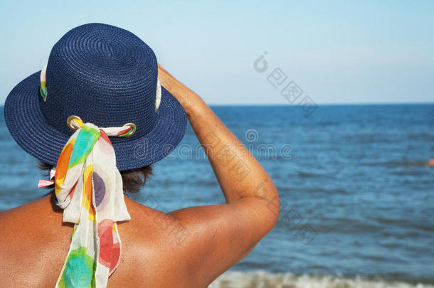 戴着沙滩帽子的老妇人望着大海