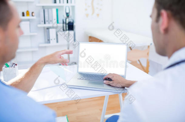 集<strong>中医</strong>疗同事使用笔记本电脑和指向屏幕