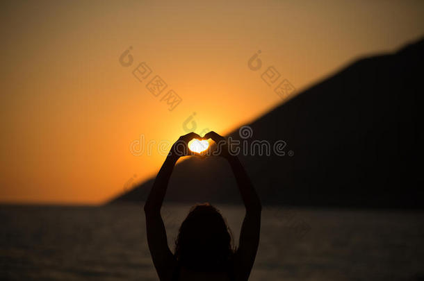 自由快乐的女人享受日落。拥抱夕阳的金色阳光，享受大自然中的宁静。假期活力