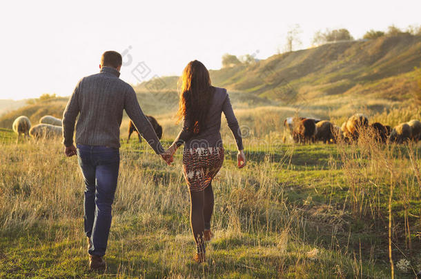 一对夫妇<strong>手拉手</strong>在秋天的草地上浪漫地散步