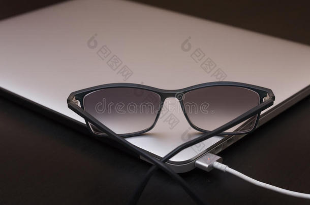 充电银色笔记本电脑上的眼镜