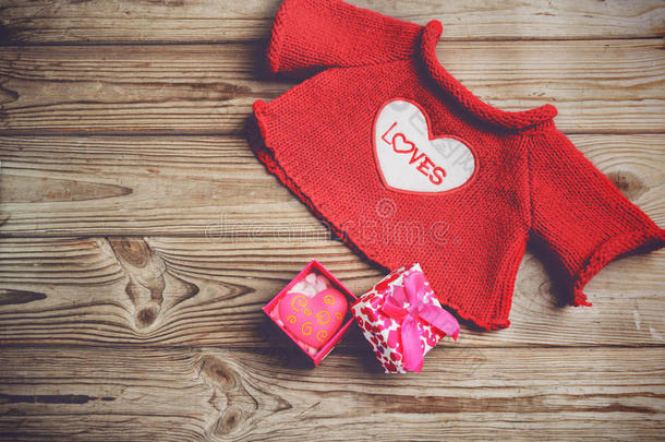 可爱的红色毛衣和礼品盒，在木制背景上有一颗心