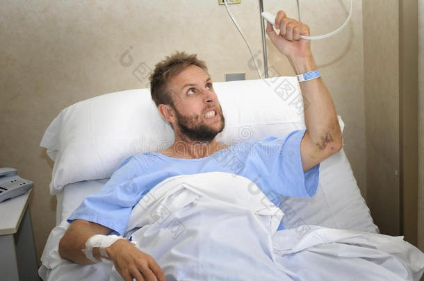 愤怒的病人男子在医院房间躺在床上按护士呼叫按钮，感到紧张和不安