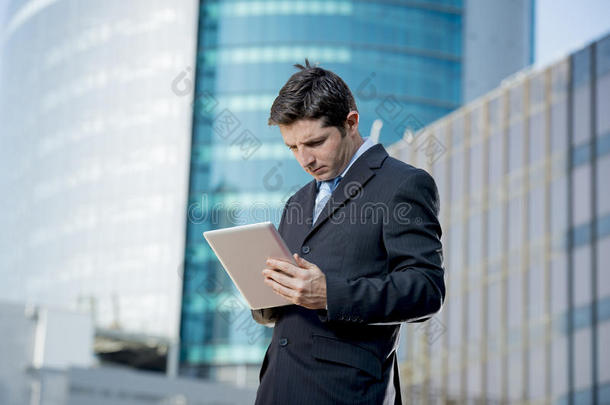 持有数字平板电脑的商人站在户外工作商业区