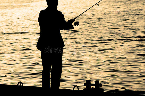 <strong>渔民</strong>站在<strong>码头</strong>边缘，在城市的河流附近有鱼竿